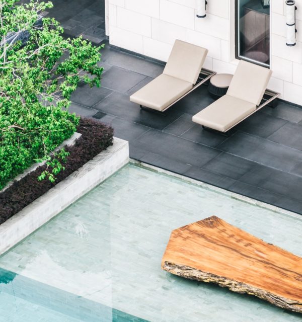 Terrasse et piscine avec carrelage extérieur posé par un artisan carreleur dans les Yvelines. Sol en dalles noires antidérapantes et revêtement de piscine en mosaïque pour un design moderne et élégant.